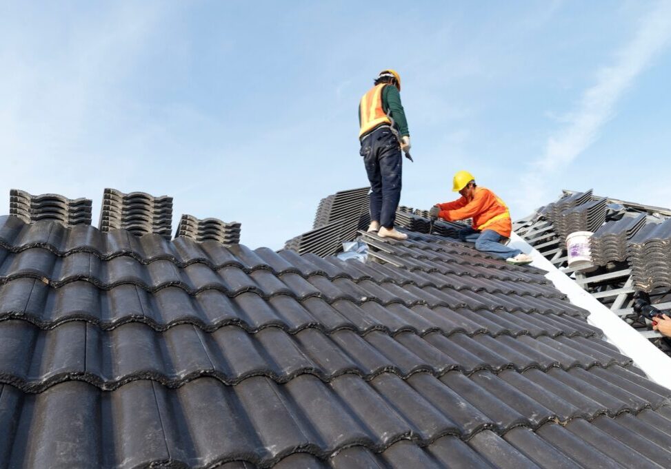 Builders in work clothes install new roofing tools, roofing tools, electric drill and use them on new wooden roofs with metal sheets