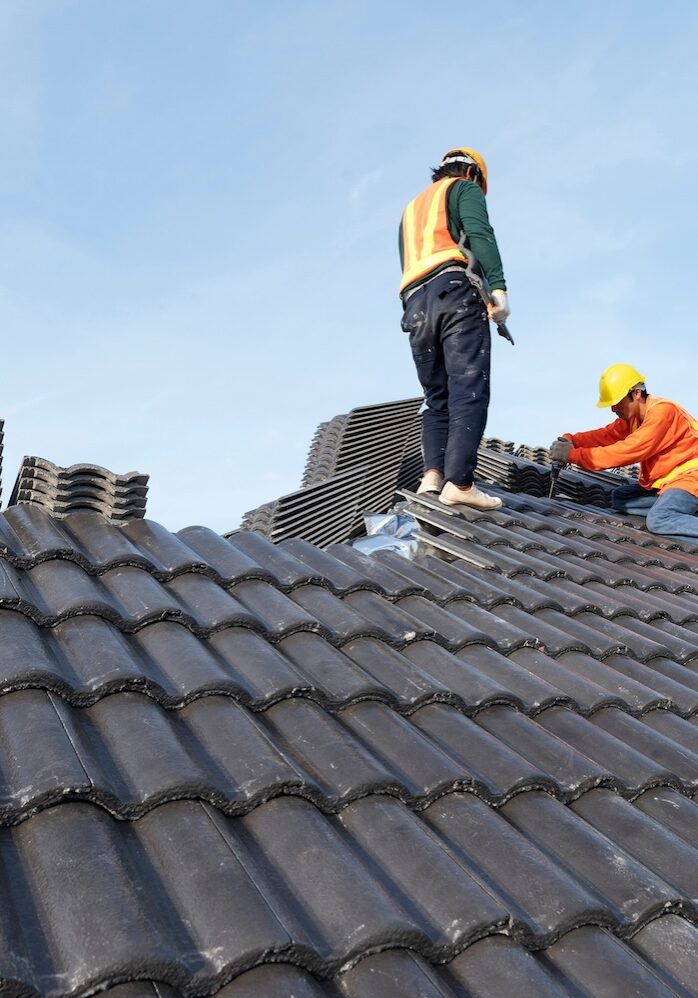 Builders in work clothes install new roofing tools, roofing tools, electric drill and use them on new wooden roofs with metal sheets