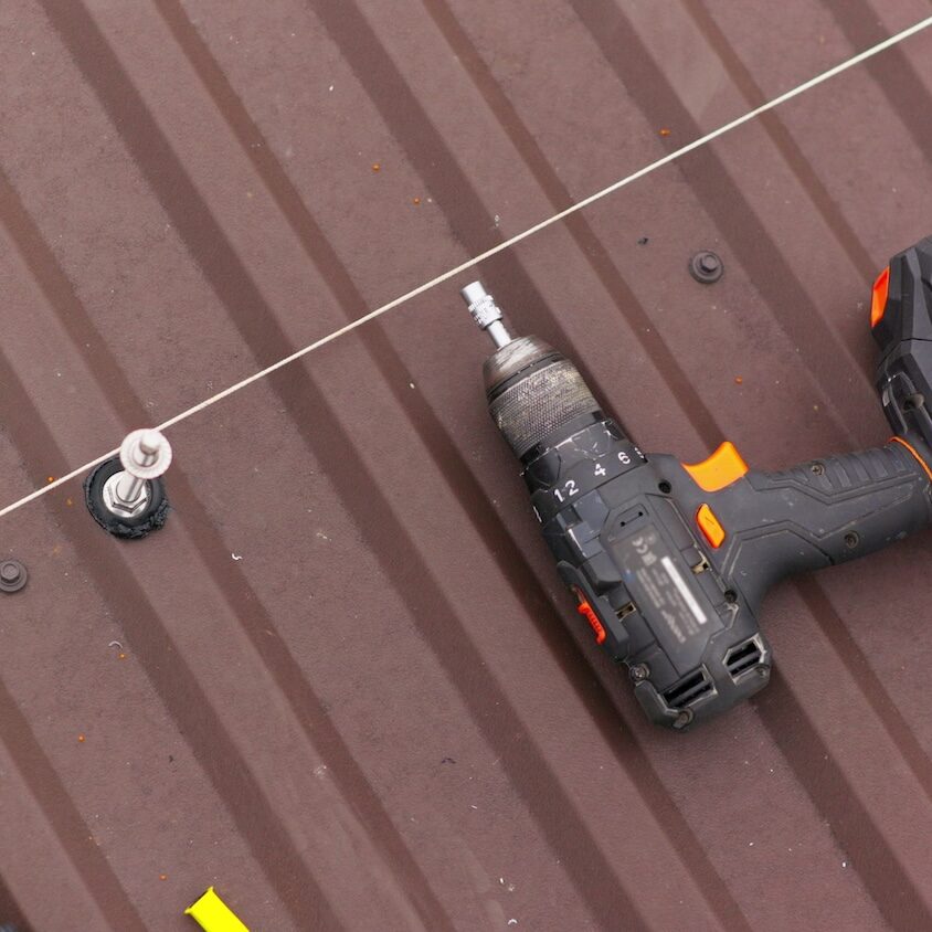 close up tool for roof repair. A screwdriver for tightening bolts and nuts lies on the roof. Installation of mounts for solar panels.