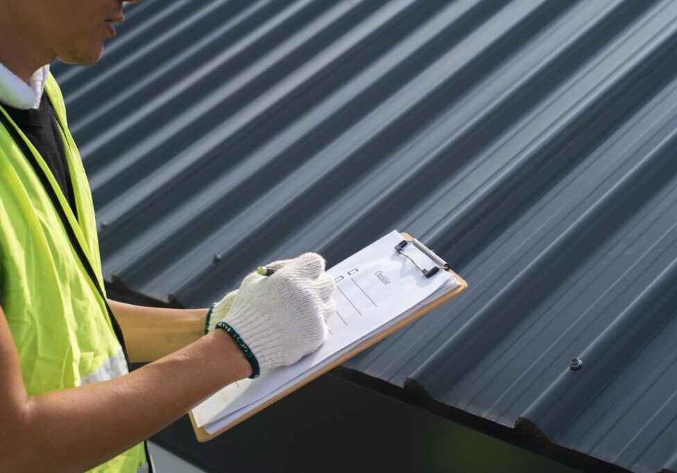 Worker, inspector, engineer is check and inspect roof house or building quality after roofing repair replace with check list in hand. Inspect and checking concept