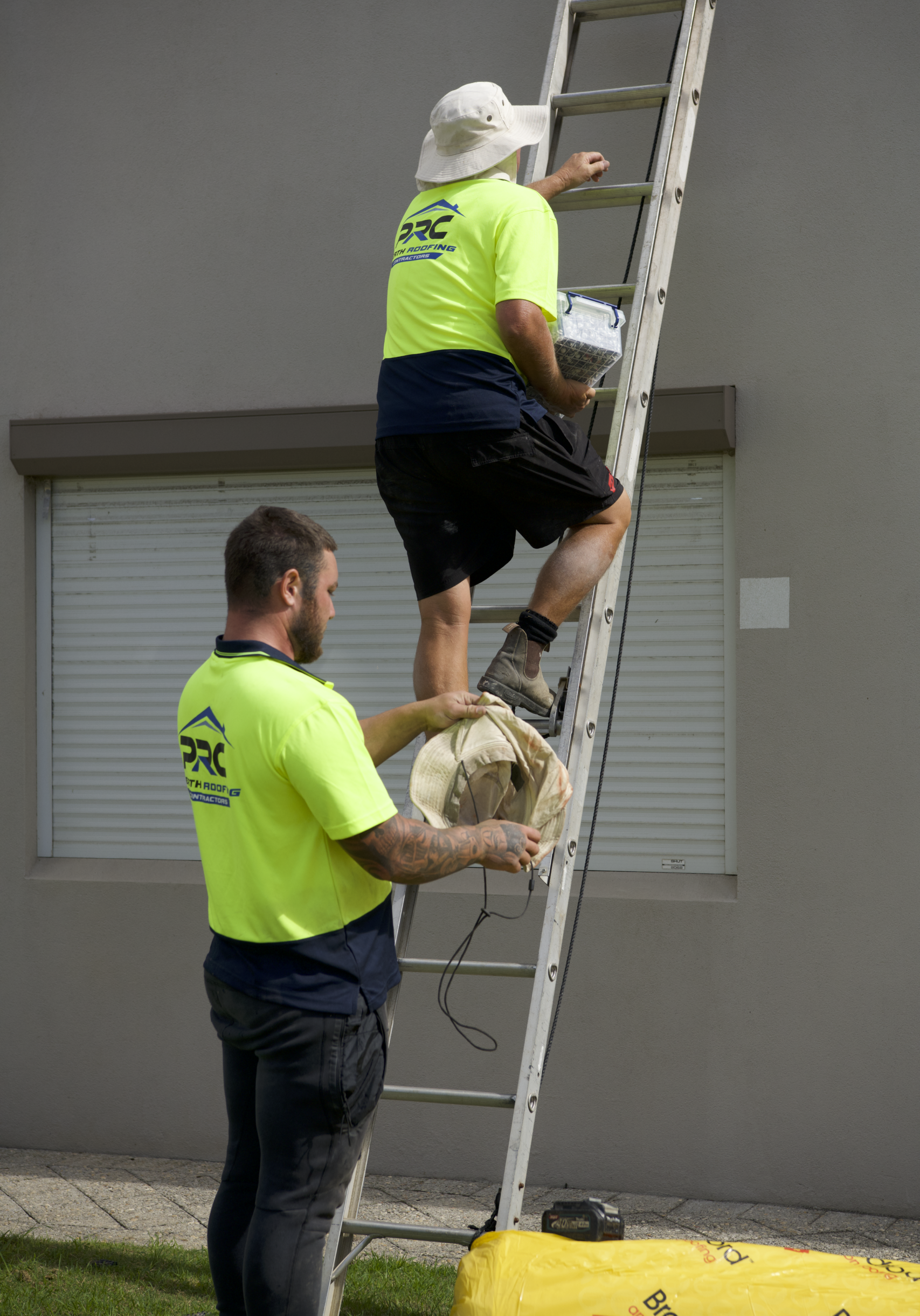 Perth roofing contractors climbing a ladder onto a commercial roof